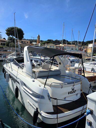 Bavaria 28 sport Bateau à moteur amarré dans un port ensoleillé, avec des yachts en arrière-plan.